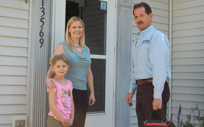 Brennan's technician at homeowner's door with homeowner and child